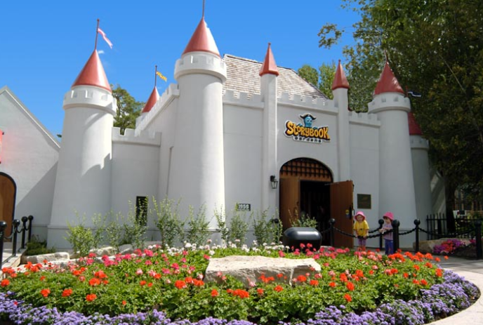 White castle with red turrets and a flower garden in front.