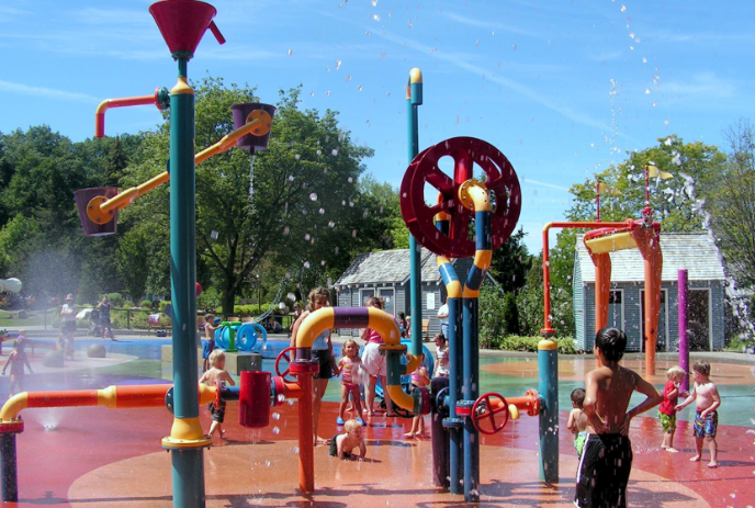 Children happily playing in the splash pad on a summer day.