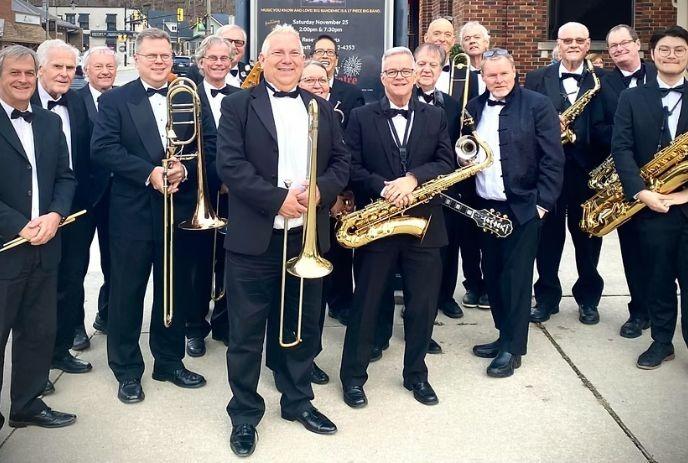 Band group with brass and woodwind instruments posing outdoors in suits.