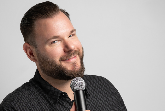 Jeff Leeson holding a microphone and smiling.
