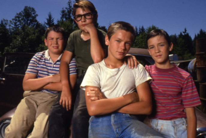 A group of young teenagers on the front of a car.