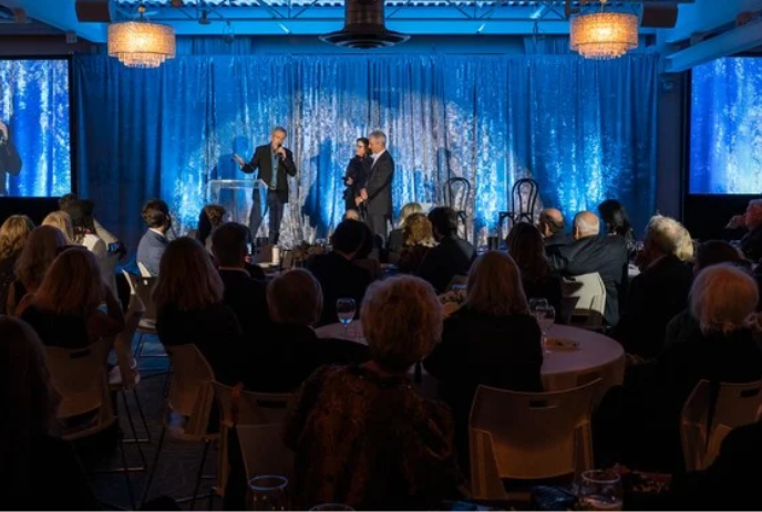 People on stage receiving an award while the audience looks on.