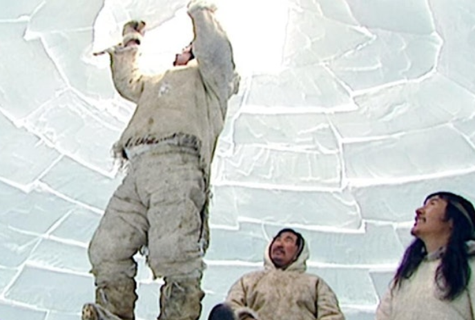 One person puts the last piece of ice in an igloo while two others look on in awe.