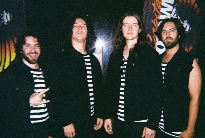 Four people in matching striped shirts and black jackets posing together before graphic backdrop.