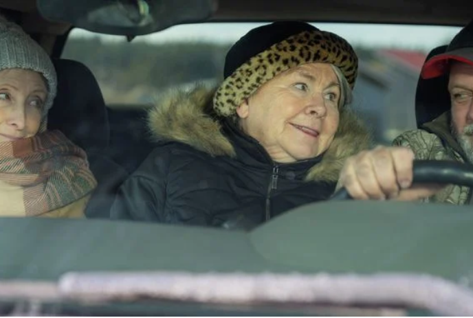 Three people sitting together in a car looking at each other.
