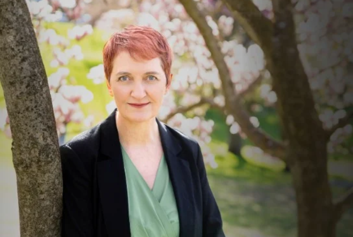 Emma Donoghue stands next to a tree with cherry blossoms in the background.