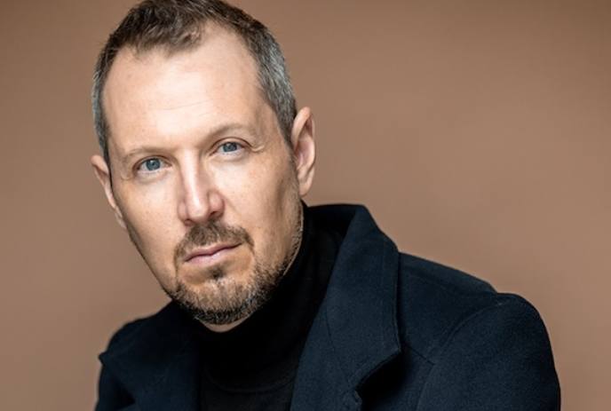 Portrait of a person wearing a dark jacket, looking directly at the camera.