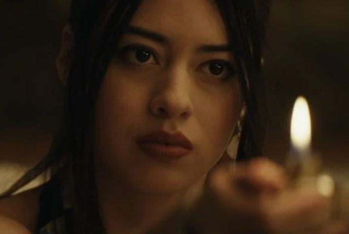 A person sits and stares intently at the flame of a lighter.