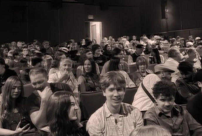 Black and white image of people sitting in a theatre.