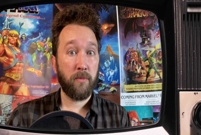 A person on a tv screen with images of He-man cartoons behind them.