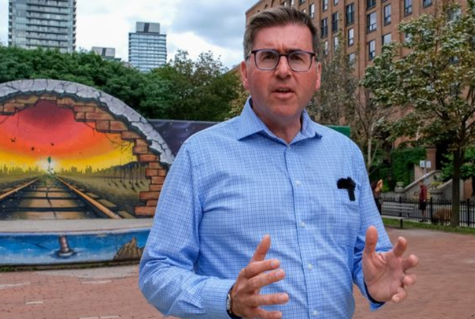 A person stands in front of a bright mural looking through a train tunnel in a residential area.
