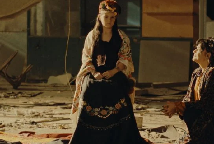 Old-fashioned image of a young person wearing an elegant dress, with another person kneeling in front of them.