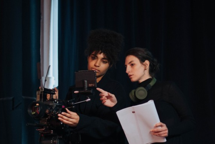 Two people standing close together looking at a small screen.
