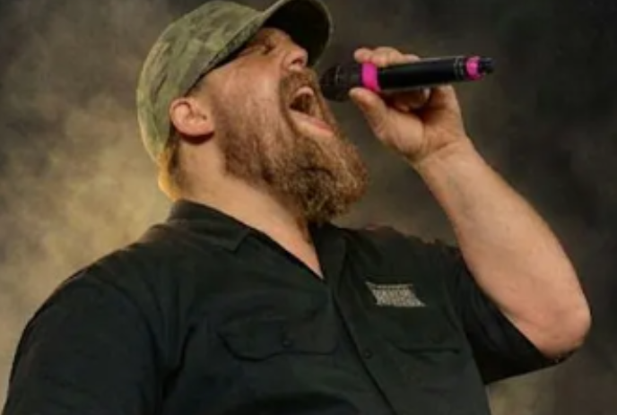 A person wearing a hat singing into a microphone.