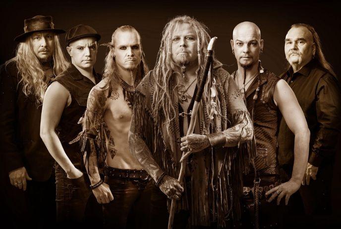 Six band members posing together in sepia tones, with one holding a staff at center.