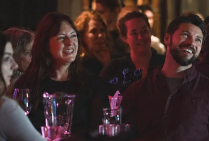 A group of people sitting around a table laugh together.