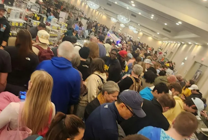 Many people crowded around tables of information and items for sale.