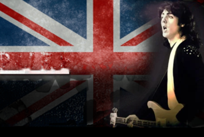 Person playing guitar in front of a Union Jack flag.