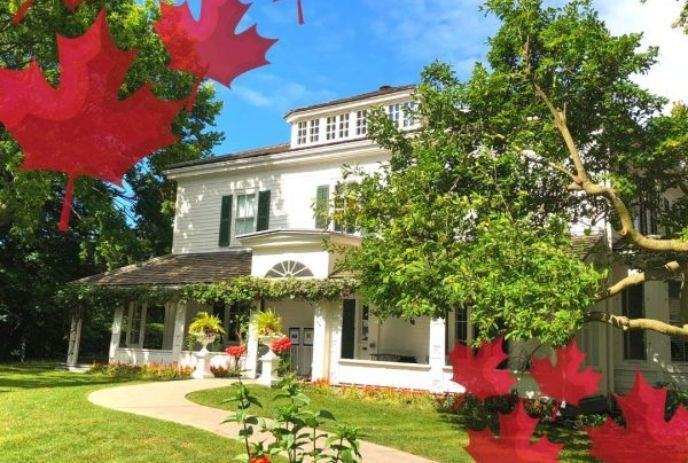Eldon House from the outside on a bright summers day, with red maple leaf graphics around it.