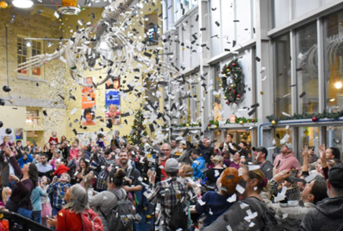 Large group of people watching as confetti falls from above.