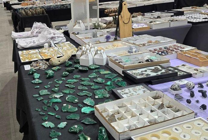 Tables at a market displaying gemstones and minerals, covered with black cloths, organized for collectors and enthusiasts.