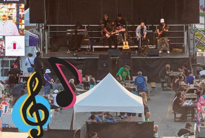 Outdoor concert with band on stage, audience seated under tent, large screen left, music notes graphic bottom left.