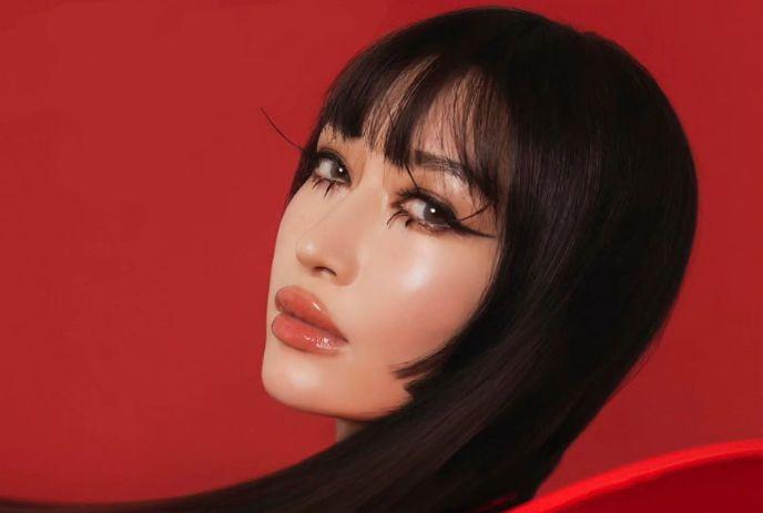 Close-up picture of Marie Vaunt with sleek dark hair, and vivid red backdrop.
