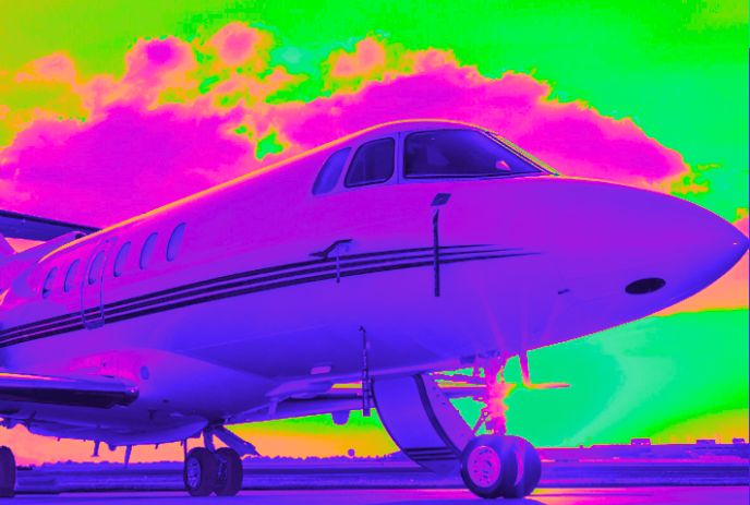 A multi-coloured plane sits on a runway with colours behind it.