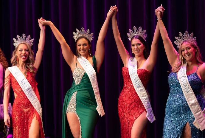 Four contestants in evening gowns holding hands up together.