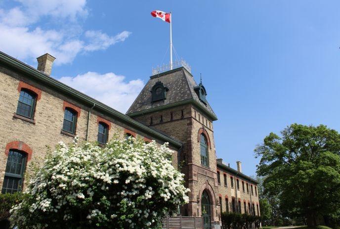 The outside of  The Royal Canadian Regiment Museum on a sunny day, with a Canadian flag flying on top.