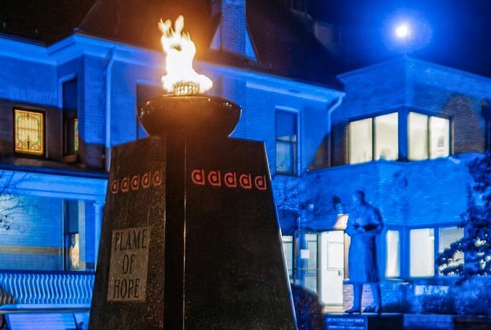 The Flame of Hope burning bright, with Banting House in the background under moonlight.