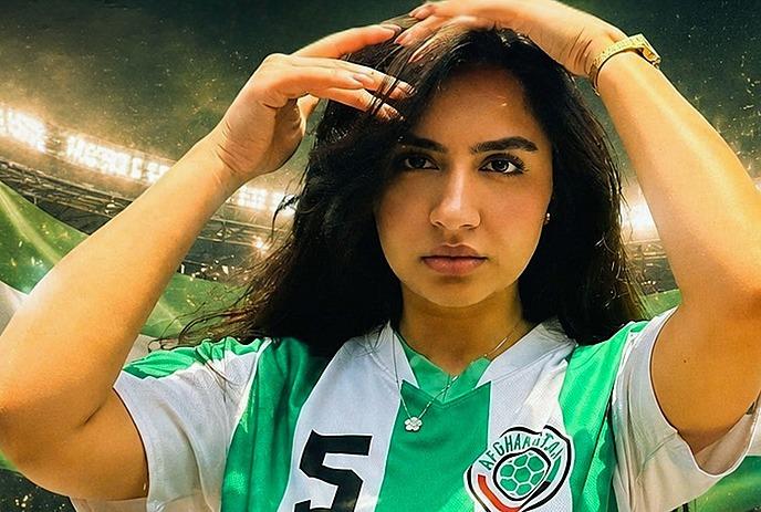 Zar The Star in green and white soccer jersey adjusting hair with stadium lights flag and microphone in background.