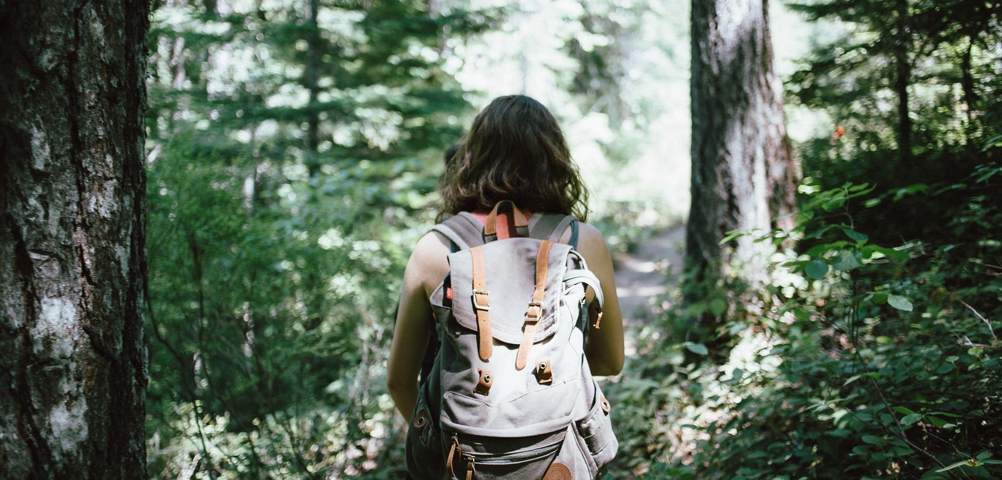 A female with a backpack hiking on a trail in Kains Woods.