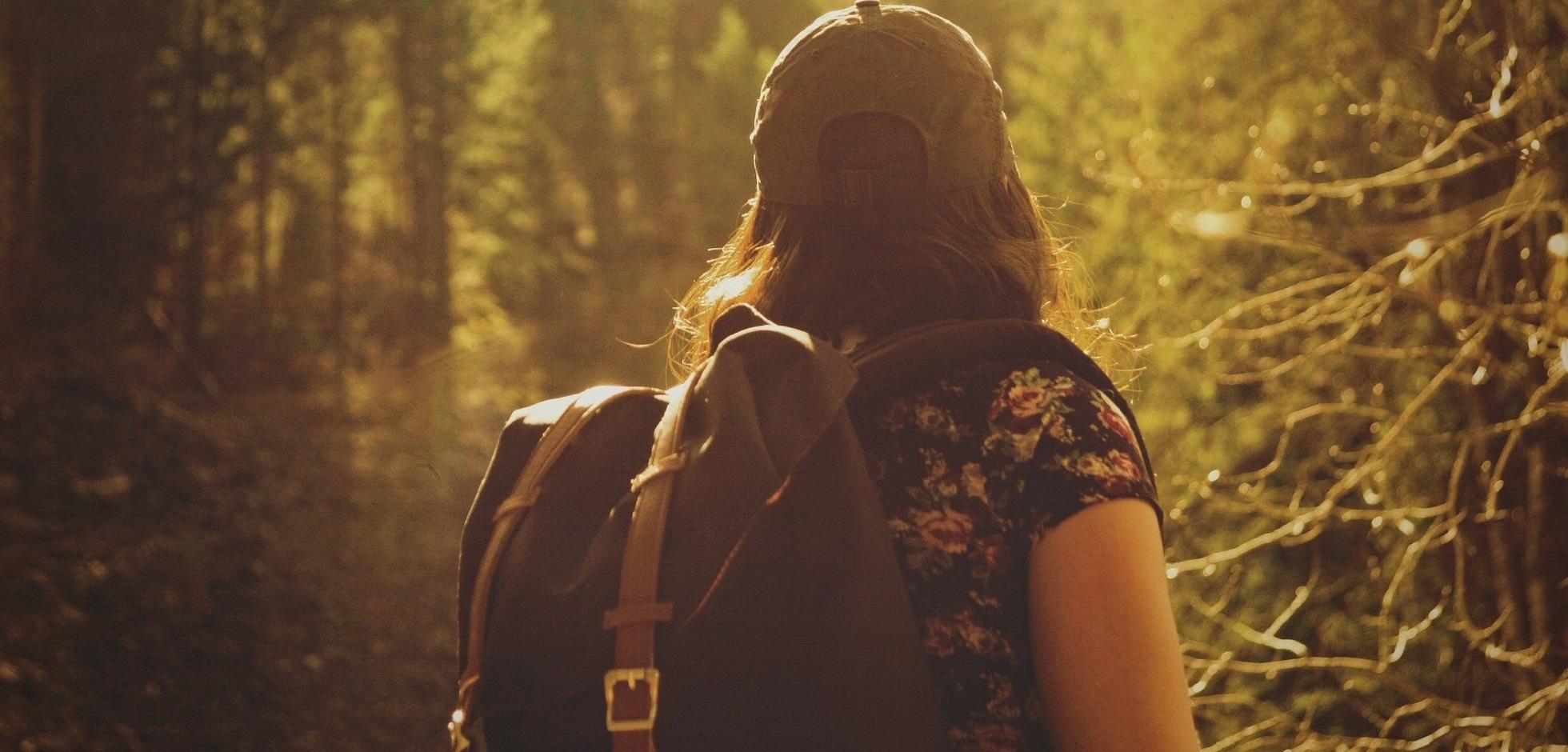 A female with a backpack hiking in a forest