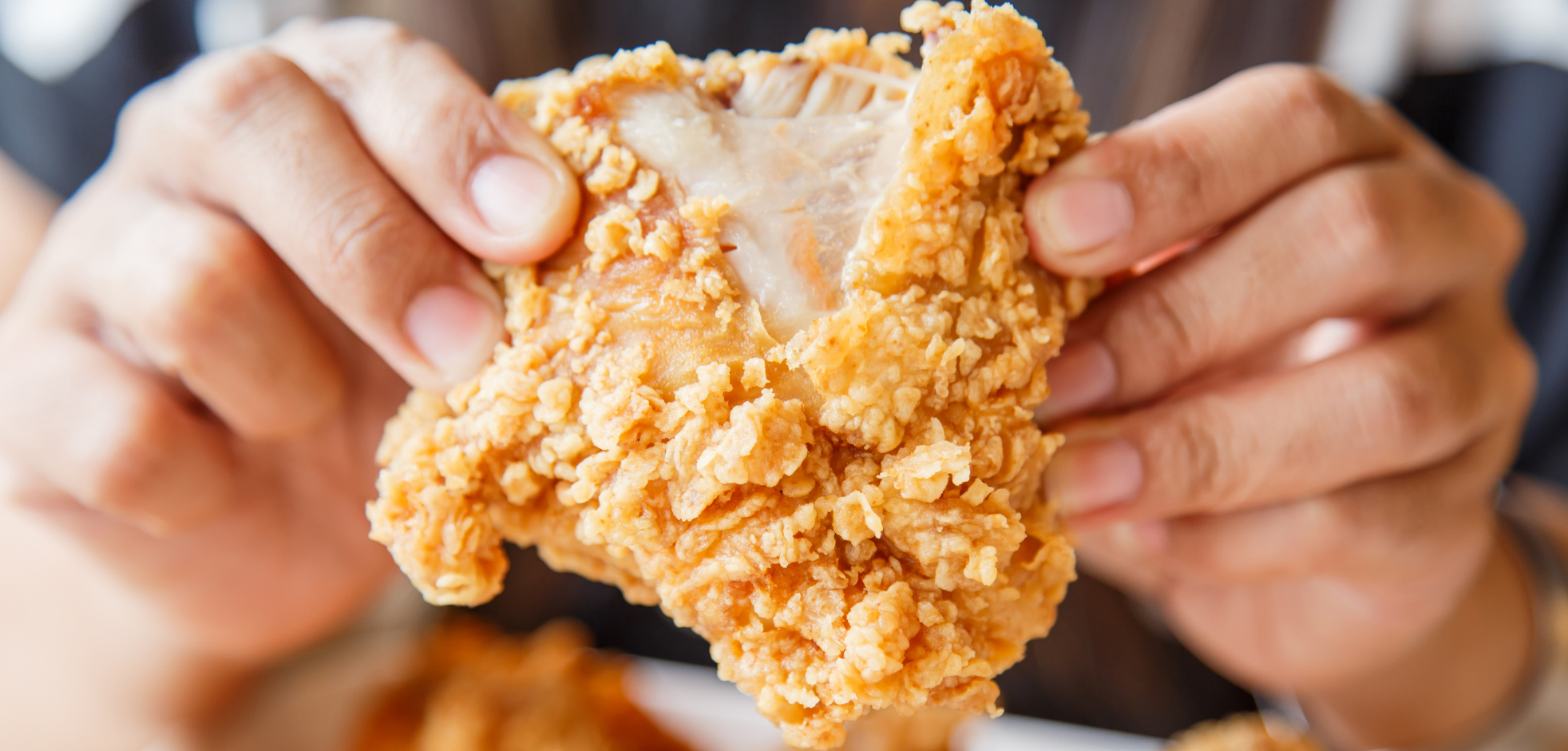 hand pulling apart a piece of fried chicken