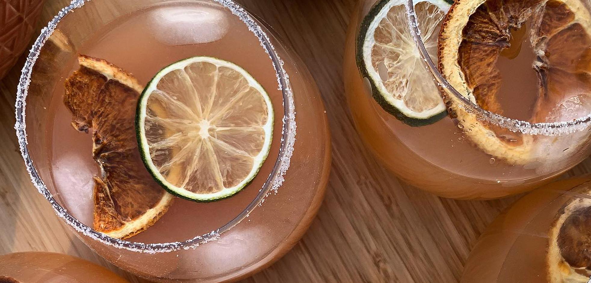 Overhead view of cocktail glasses rimmed with sugar and pieces of lemon and blood orange floating within them