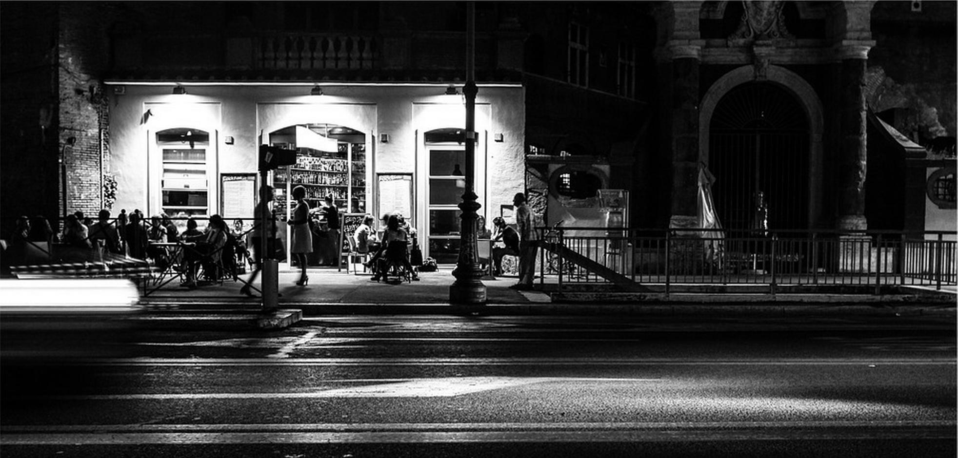 Groups of people sitting outdoors at tables on a patio at night in London, Ontario