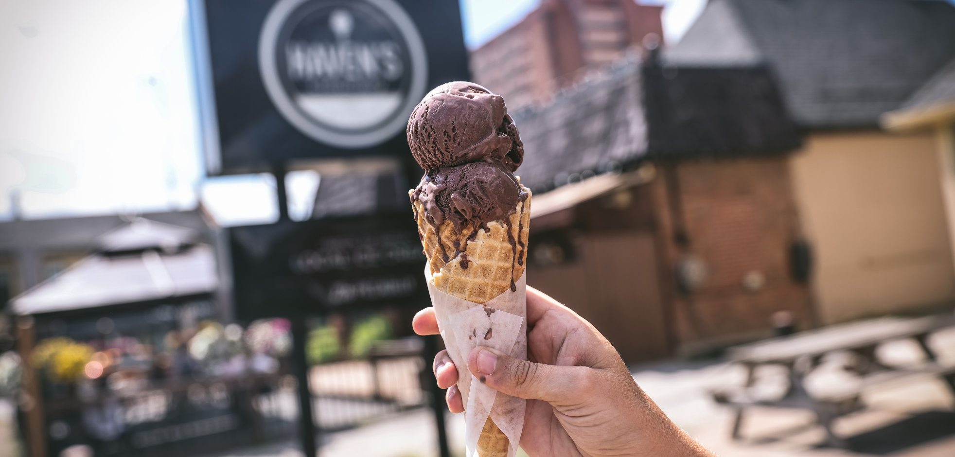 hand holding a chocolate ice cream cone in front of Haven's Creamery in London, Ontario