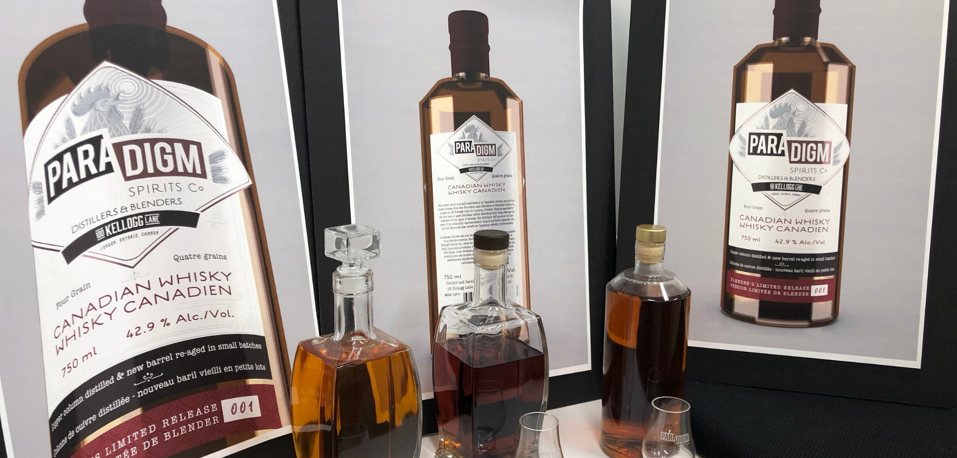 three bottles of whiskey on display from Paradigm Spirits Co. with empty glasses in front