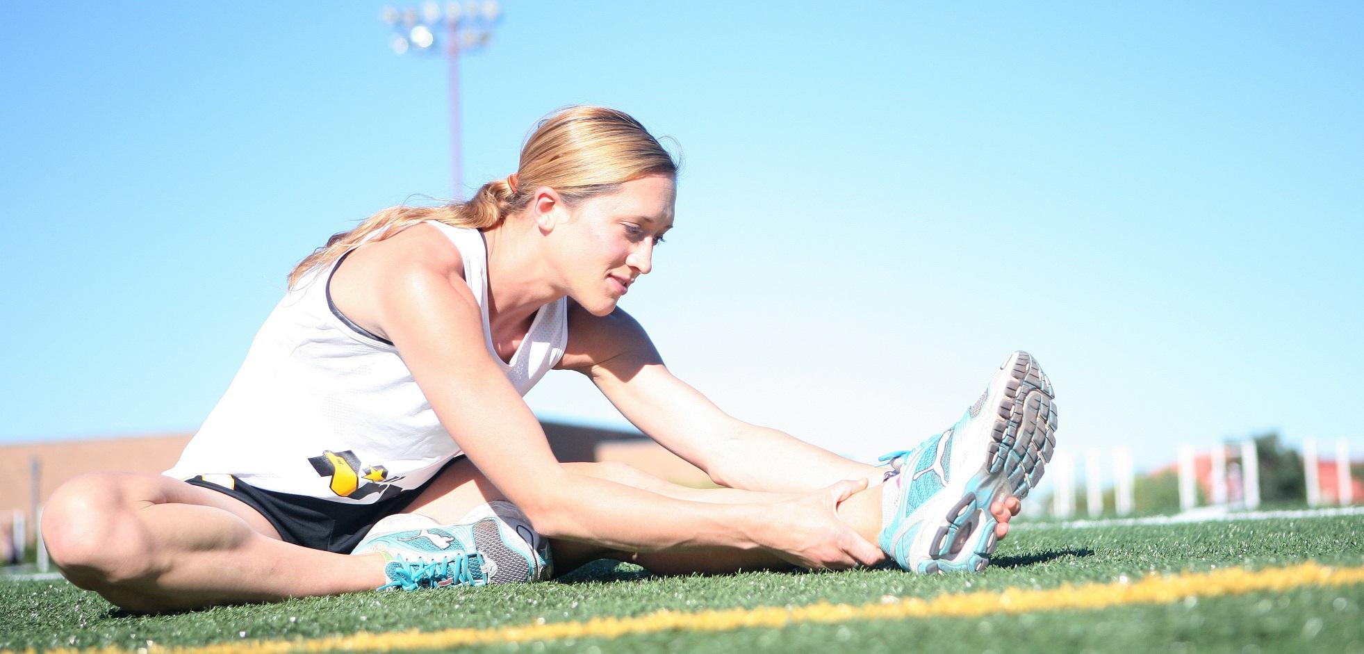 A female athlete stretching on a field