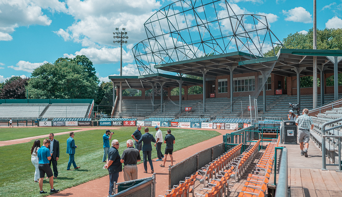 people standing on a baseball field talking with media