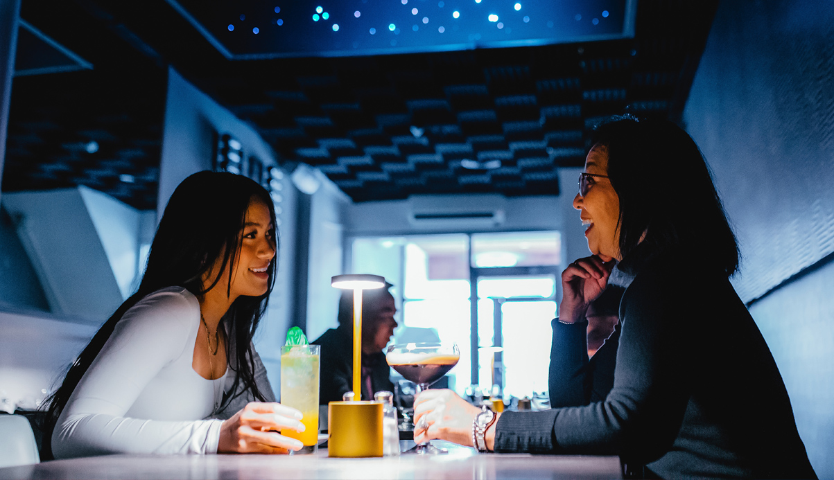 two people sitting at a table enjoying some drinks