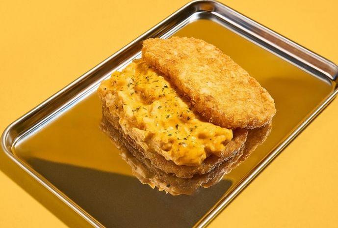 Golden grilled cheese sandwich served in a metal tray on a bright yellow background.