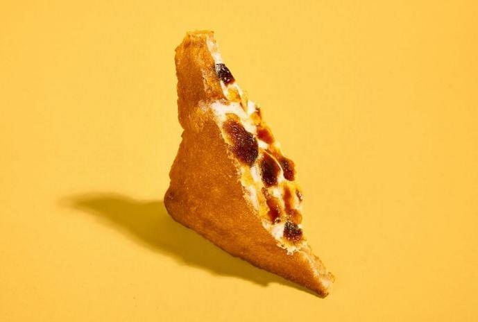 Triangular toasted sandwich filled with melted cheese, photographed on a yellow background.
