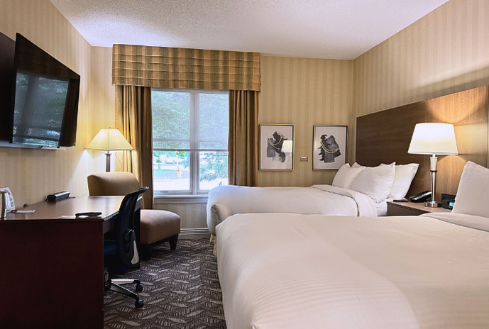 Inside a room with two beds, a desk and chair and a television.