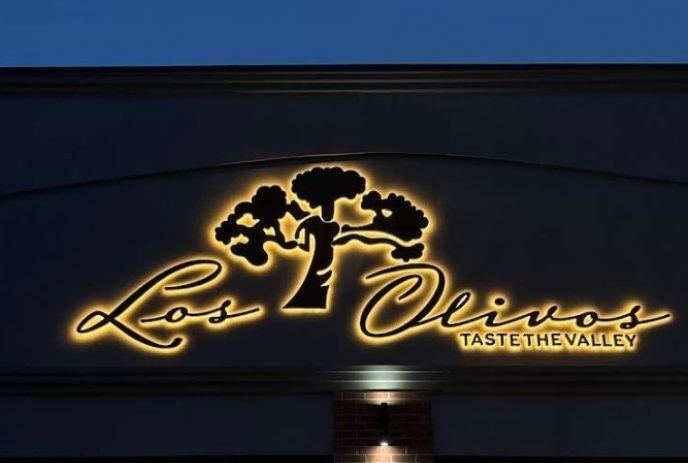 Olive oil pours beside fresh olives; “Los Olivos” logo with tree and “TASTE THE VALLEY” text evokes freshness.