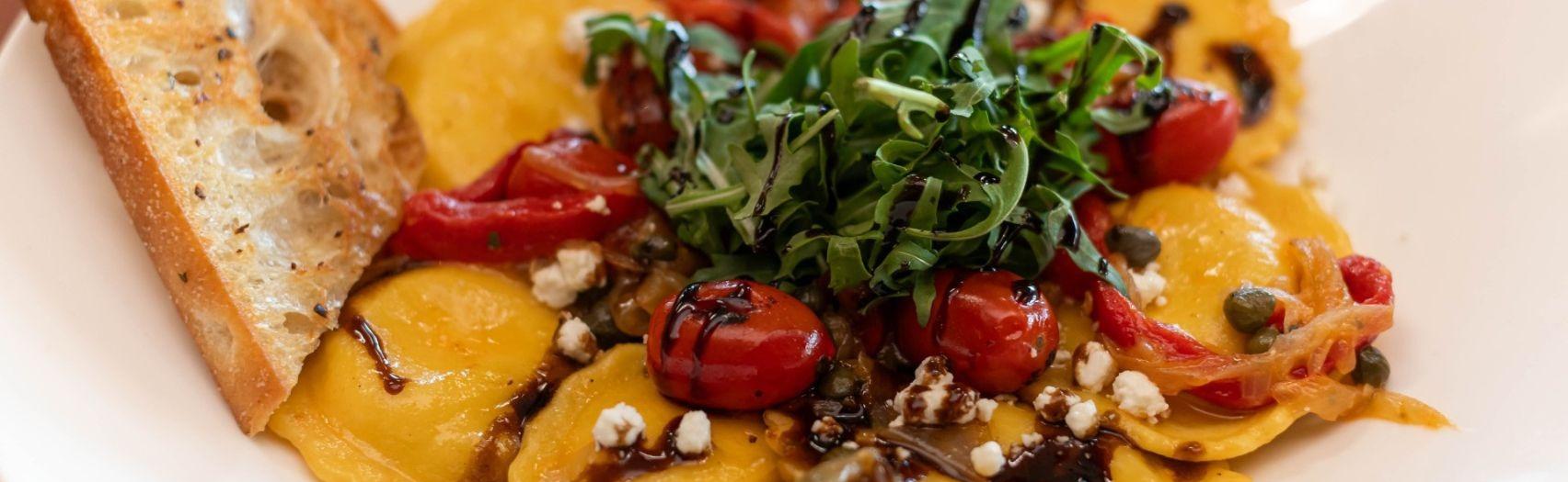 Cheese ravioli topped with roasted tomatoes, arugula, balsamic glaze, and toasted bread.