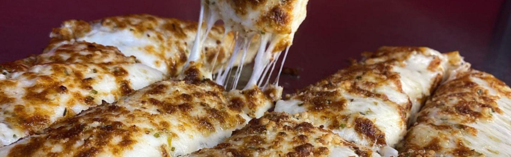 Cheesy breadsticks being pulled apart with melted, stretchy cheese