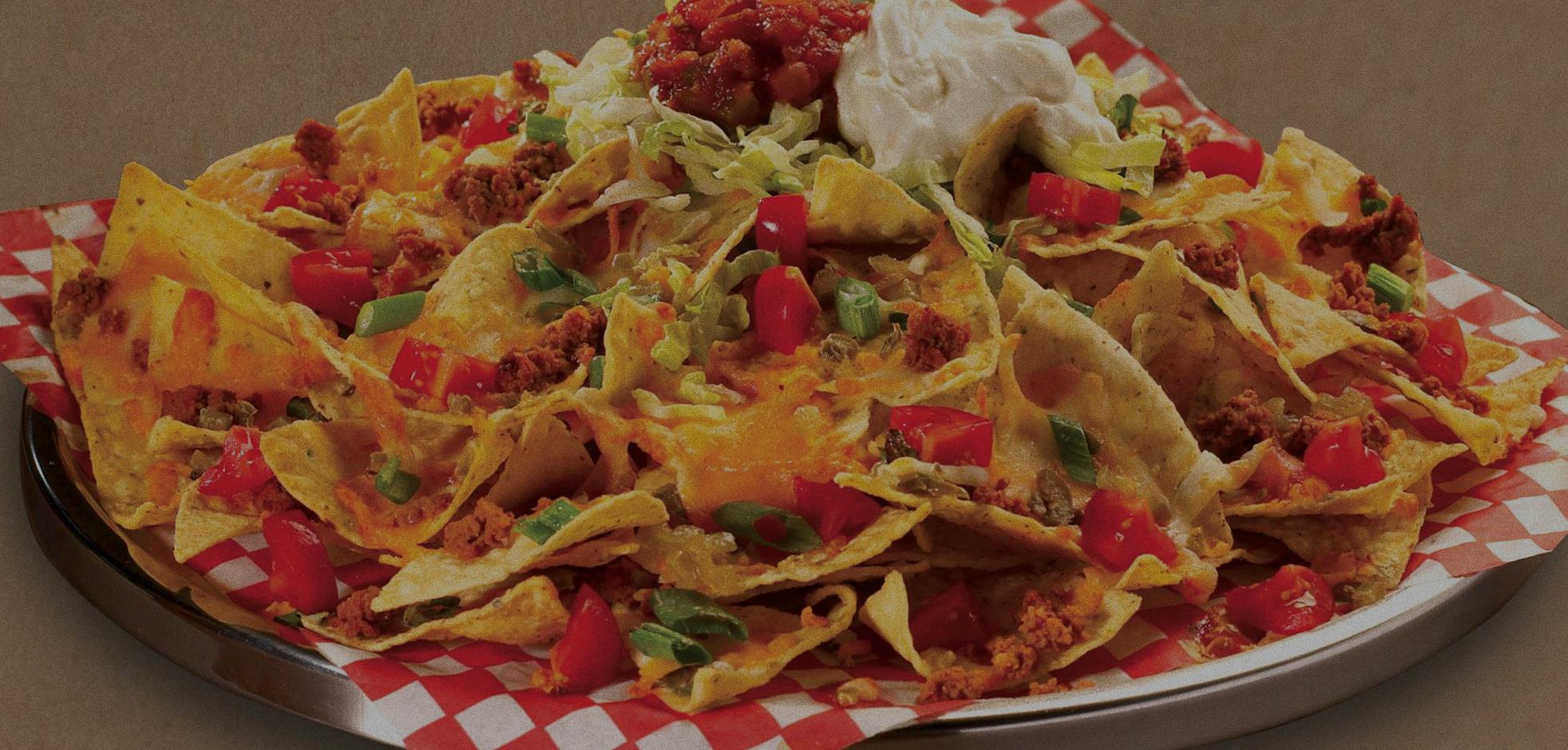 plate of nachos and cheese with diced tomatoes and other toppings