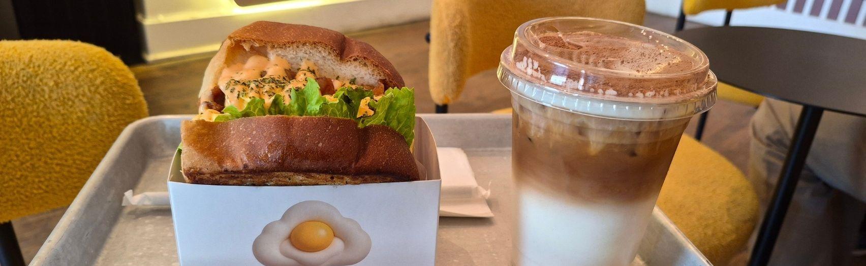 An egg sandwich with an iced coffee on a serving plate at Egg Cloud.